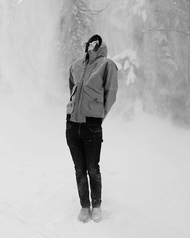 Man standing staring up into snow falling around him